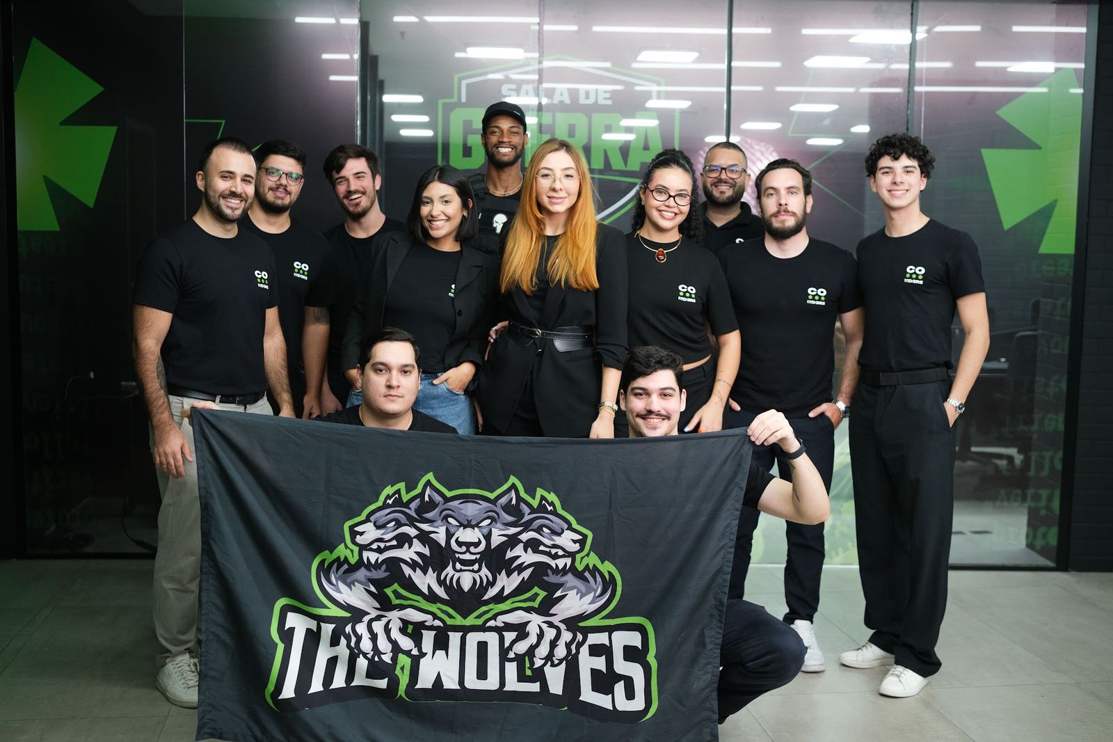 Time comercial da Coders — 'The Wolves' — reunido na sede em Florianópolis, com a bandeira do time e o logo da Coders ao fundo.