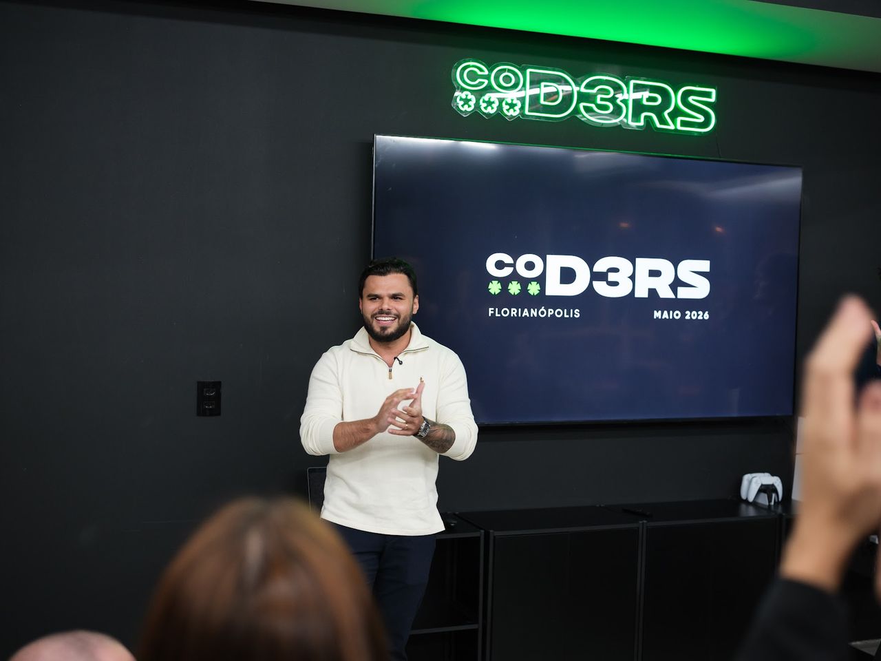 Apresentação na sede da Coders, em Florianópolis, com o logo da empresa ao fundo.
